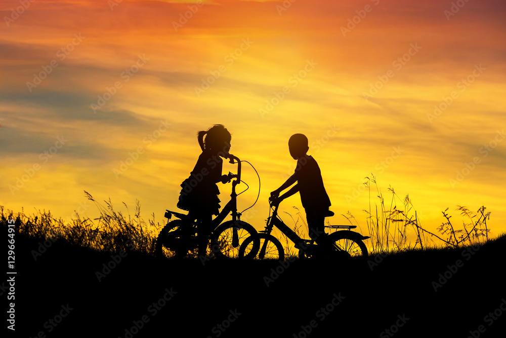 silhouette little boy and little girl having fun riding bike on sunset silhouette little boy and little girl having fun riding bike on sunset