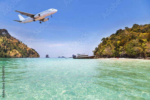 passenger airplane flying above small island in tropical sea. travel destinations concept
