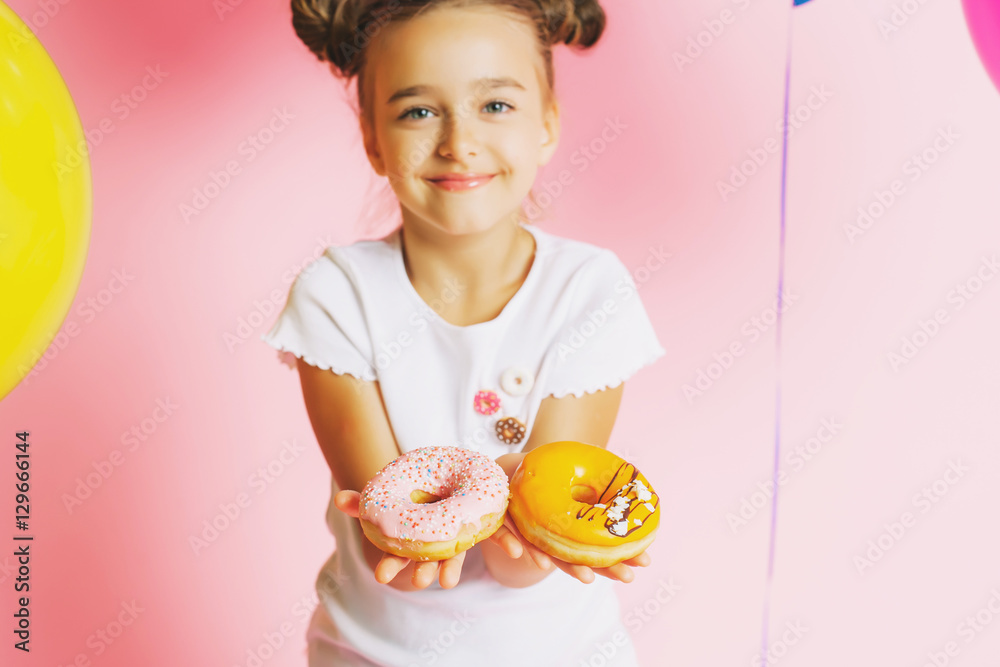 Little girl with bright balloons and donuts on a pink background Little girl with bright balloons and donuts on a pink background