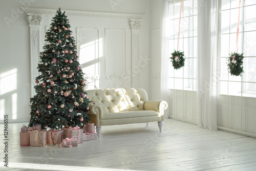 large white living room with a vintage sofa and a large Christmas tree with gifts and large panoramic windows © Корнеевец-Выдренкова