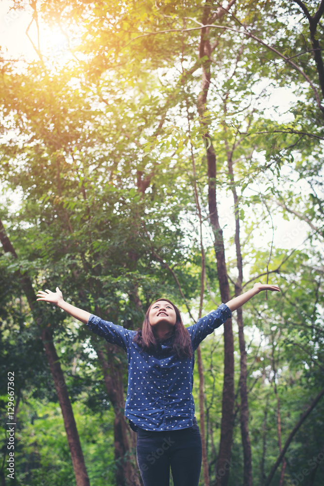 Attractive young woman standing in a forest, hands spread around