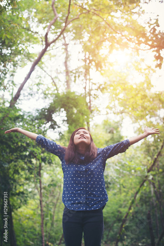 Attractive young woman standing in a forest, hands spread around