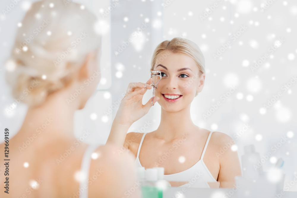 woman with curler curling eyelashes at bathroom woman with curler curling eyelashes at bathroom
