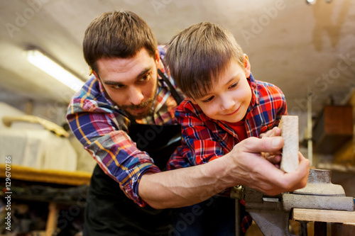 father and little son with wood plank at workshop