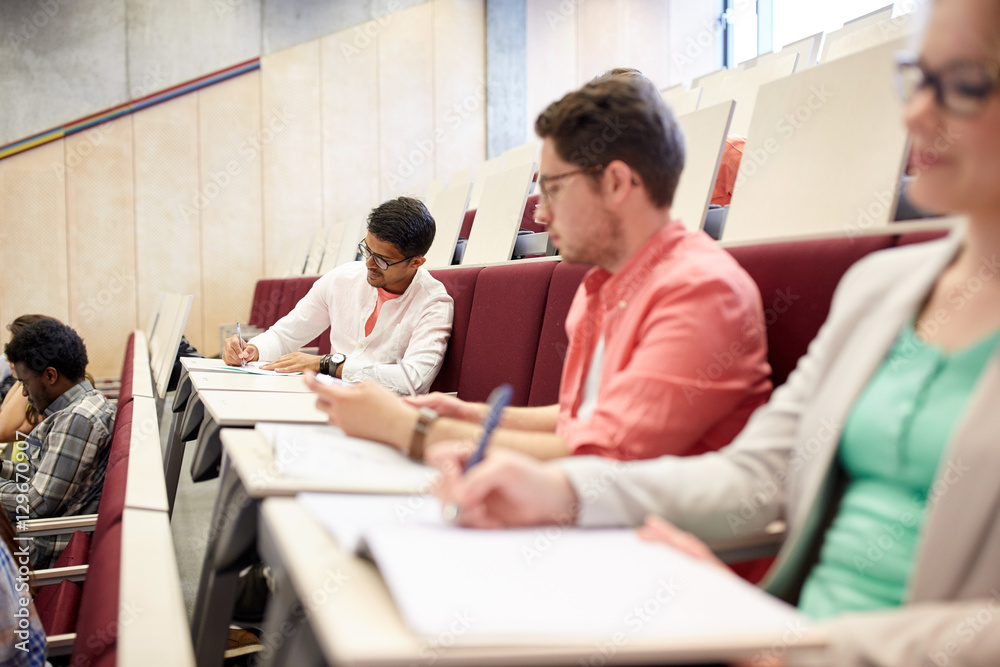 group of students with notebooks in lecture hall group of students with notebooks in lecture hall