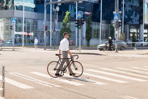 young man with bicycle on crosswalk in city