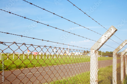 Fence with barbed wire with a blue sky background.