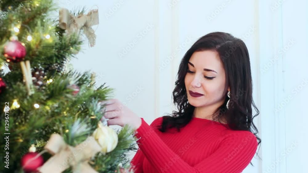 Beautiful Girl Decorates a Christmas Tree at Christmas. She Smiles Beautifully. She is Very Beautiful and Attractive. New Year 2017. Beautiful Girl Decorates a Christmas Tree at Christmas. She Smiles Beautifully. She is Very Beautiful and Attractive. New Year 2017.