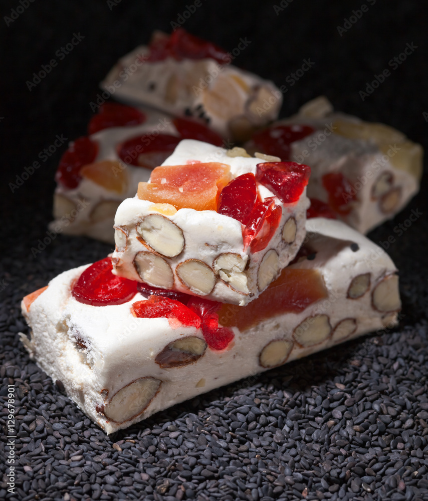 Soft nougat with tropical fruit and berries on a black sesame Soft nougat with tropical fruit and berries on a black sesame