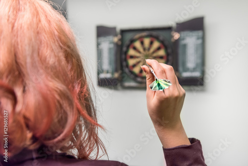 Closeup of young woman's head and hand throwing a dart