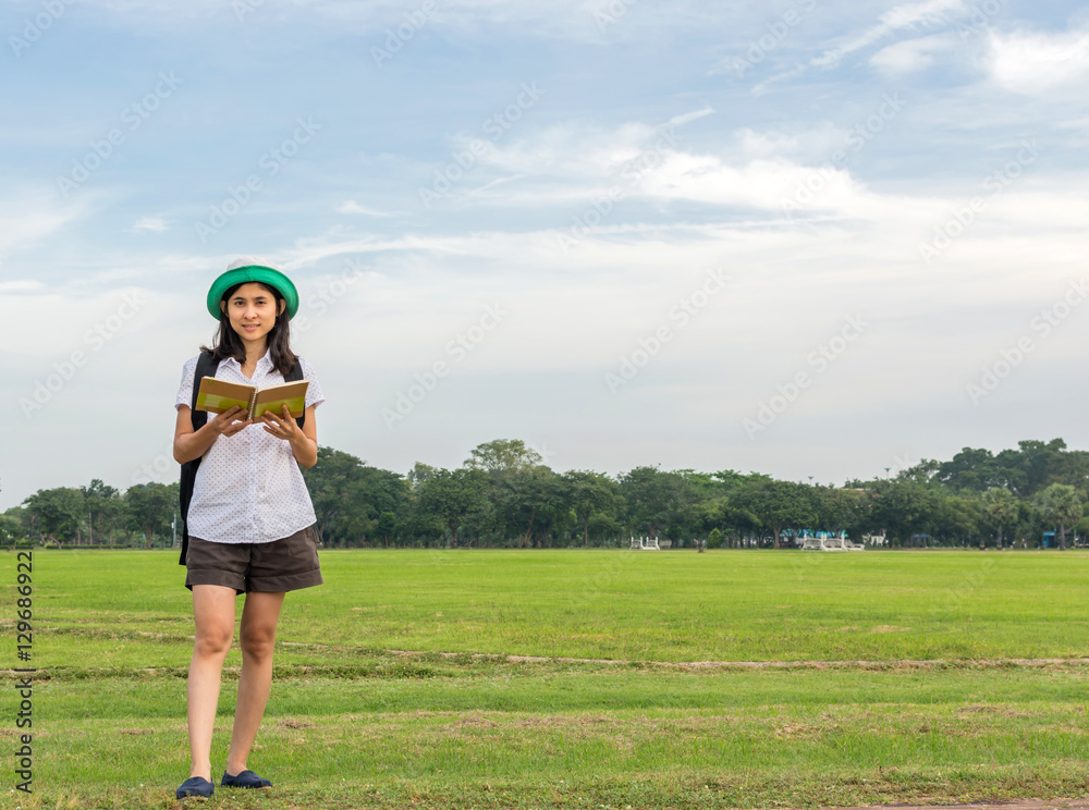 young woman carry backpack and reading book in green field, outd young woman carry backpack and reading book in green field, outd