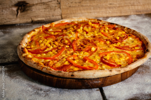 Pizza with tomatoes and corn isolated on wood background