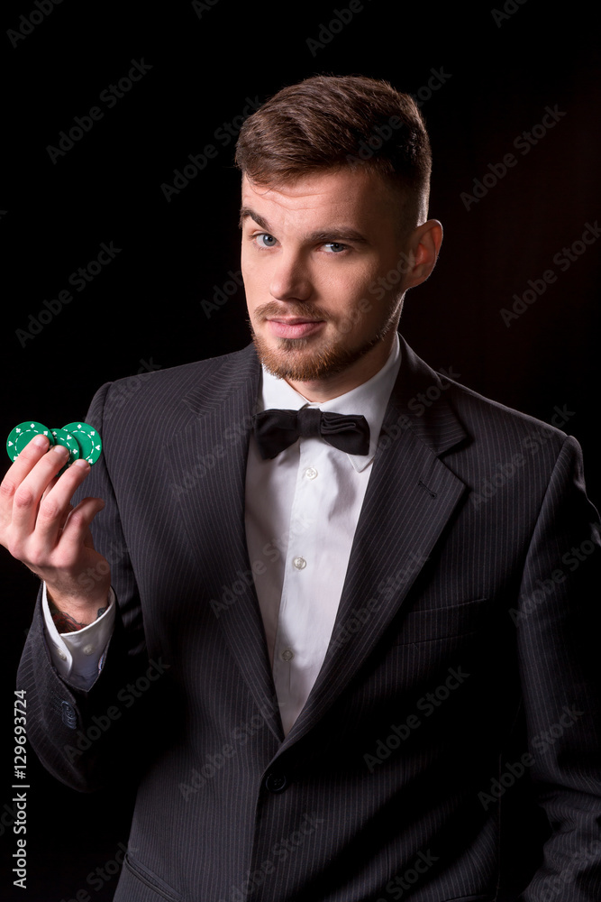 man in a suit posing with chips for gambling
