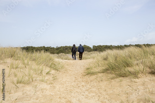 Two men walking in the dunes on a beach of L'aiguillon sur Mer, Vendee, France © Melanie