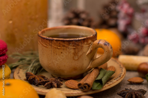 Cup of coffee, macaroons, cookies, walnuts, hazelnuts, cinnamon sticks, star anise, cone, candle, fir branch on sackcloth fabric