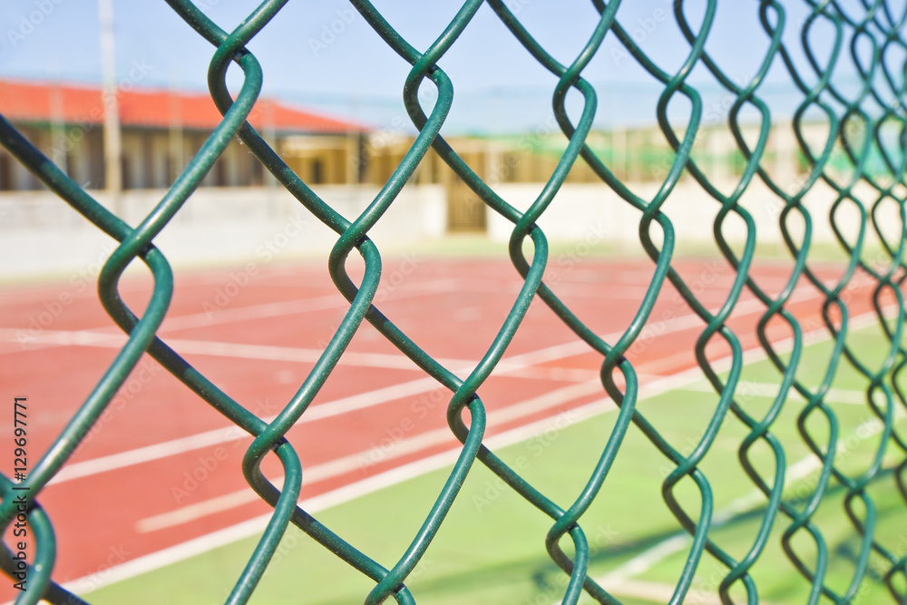 Fototapeta premium Wire metal mesh against a tennis court - concept image