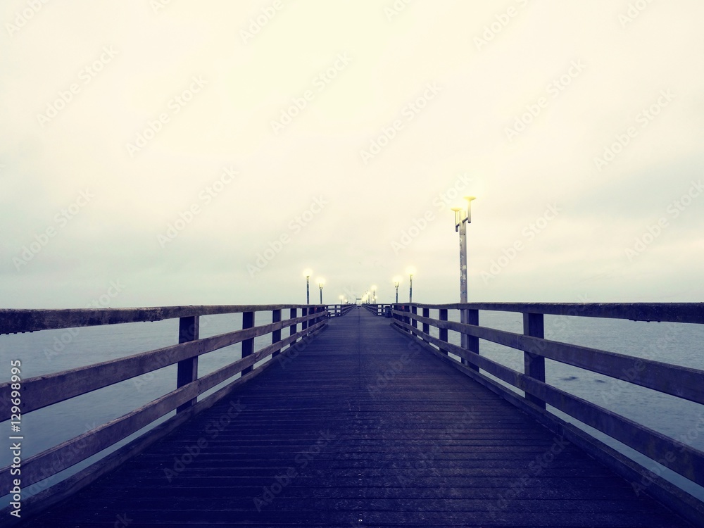 Autumn dark mist on wooden pier above sea. Depression, dark atmosphere.