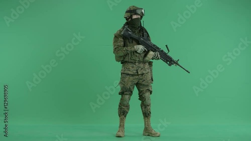 serviceman standing with weapon and looking at side at green screen