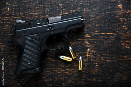 Gun and ammunition on dark wooden table. top view