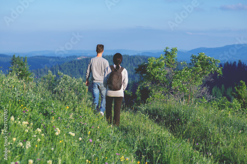 Young couple with backpacks hiking in the mountains and enjoying valley view.Colored photo