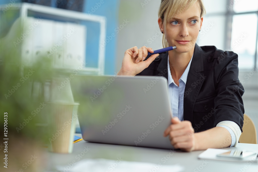 junge frau sitzt nachdenklich am laptop im büro junge frau sitzt nachdenklich am laptop im büro