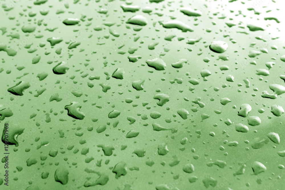 Rain drops on green metal surface with blur effect