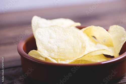 Close-up of a dish with chips standing on dark gray colored wooden table. Vertical studio shot