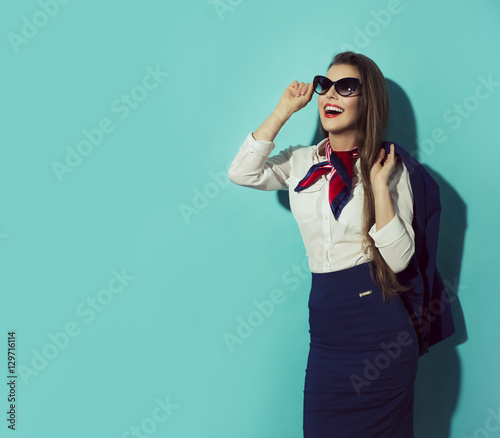 Happy stewardess with sunglasses on blue background looking left. photo