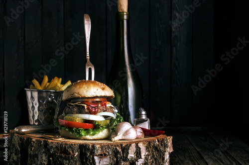Delicious burger with fries and garlic on dark rustic background
