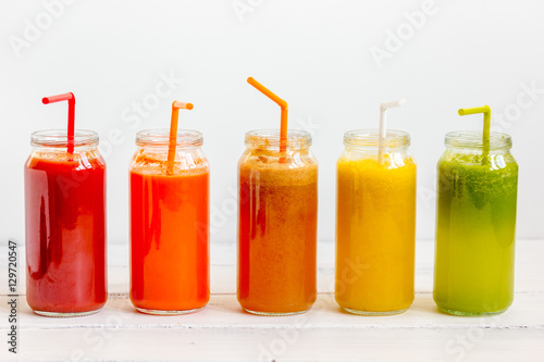 Fresh detox juices glass in row bottles on white background