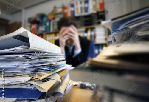 Obraz na plátně Frustrated man sitting desperate over paper work at desk