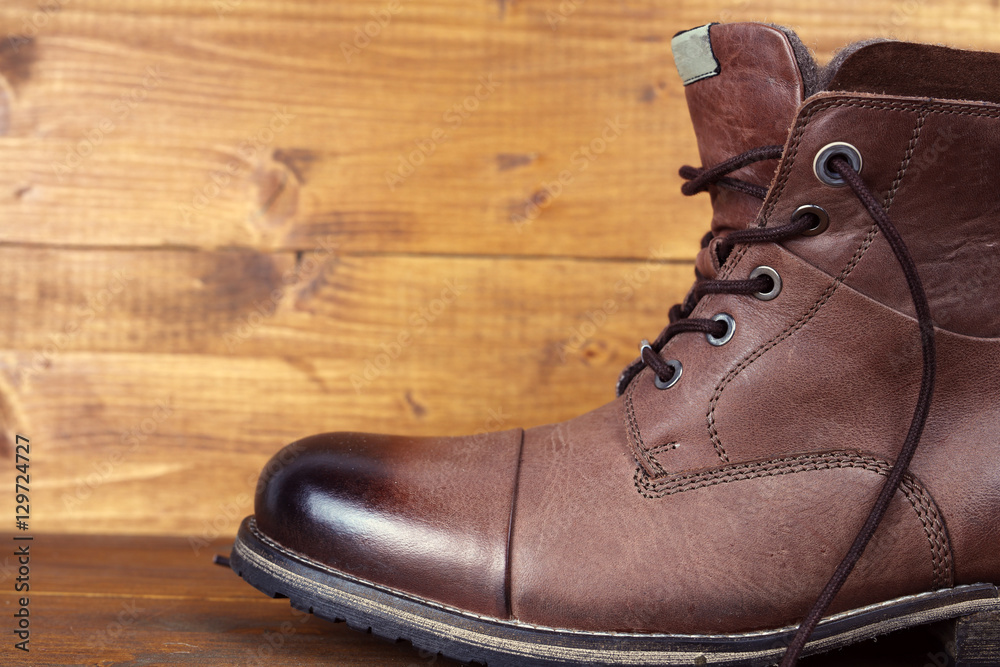 Brown leather winter mens high boots, shoes on vintage wooden background