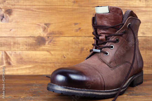 Brown leather winter mens high boots, shoes on vintage wooden background
