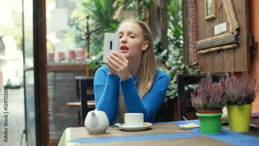 Girl using smartphone as a mirror while painting lips and smiling to the camera
Girl using smartphone as a mirror while painting lips and smiling to the camera