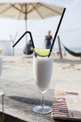 Cocktail glass with two straws and with beach landscape background photo