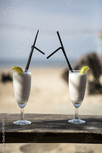 Cocktail glass with two straws and with beach landscape background photo