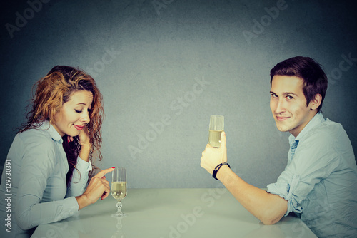 Sly man and skeptical woman sitting at table drinking wine photo