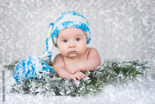 Newborn baby in a knitted cap. Snow background