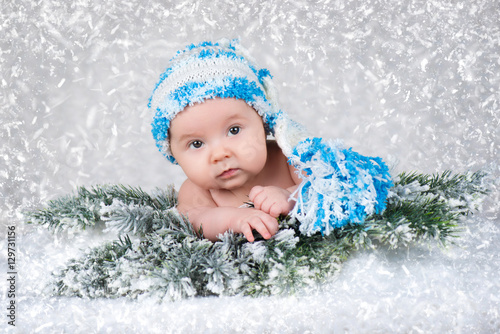 Newborn baby in a knitted cap. Snow background