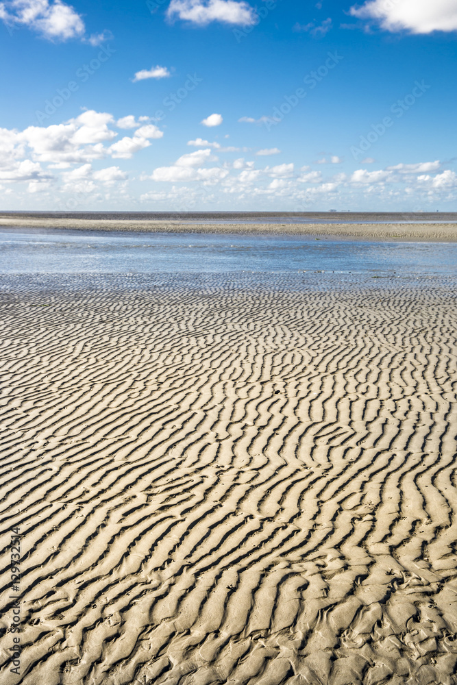 Maritime landscape with blue sky white clouds and pattern in the sand, Waddenzee - Wadden Sea, Friesland, The Netherlands