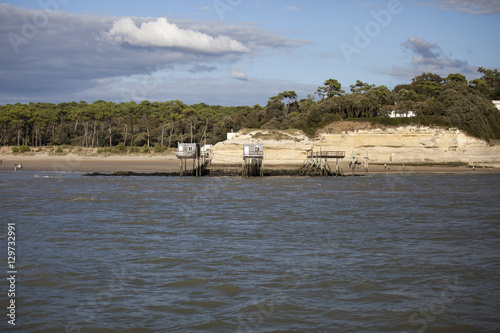 View from the Gironde estuary with the limestone cliff of the village of Meschers sur Gironde and its troglodytic houses and traditionnal typical wooden fisherman cabins, Charente maritime, France