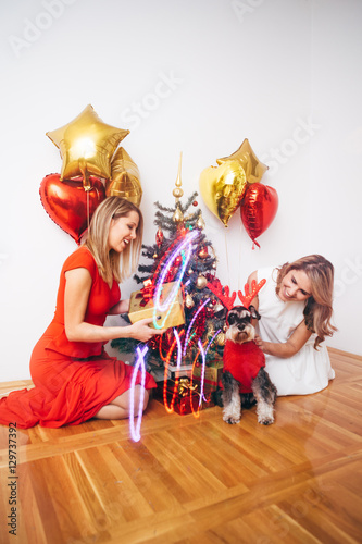 Two woman and dog sharing gifsts for Christmas/ New Year