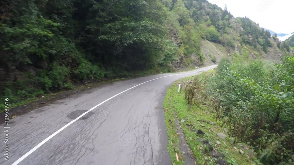 Narrow winding road in mountains surrounded by trees, dangerous driving Narrow winding road in mountains surrounded by trees, dangerous driving