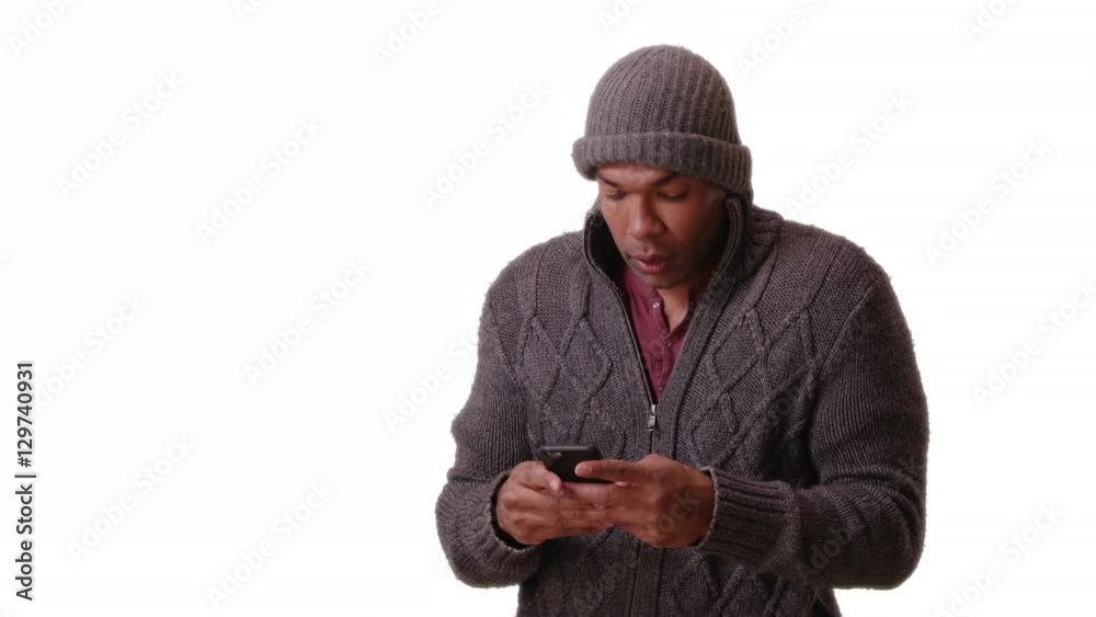 An African American man stands trembling on a white background on his smart phone An African American man stands trembling on a white background on his smart phone