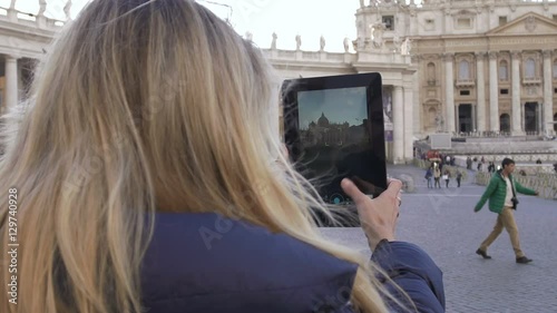 young cute woman making photos with tablet to St. Peter Church in Rome photo