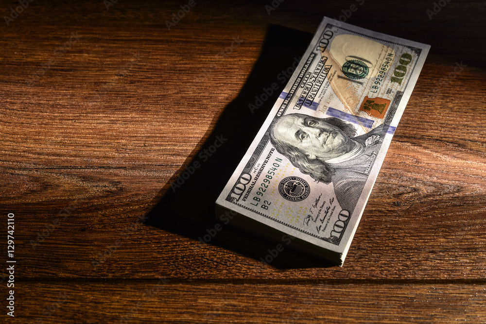 Stack of American dollars lie on wooden boards Stack of American dollars lie on wooden boards