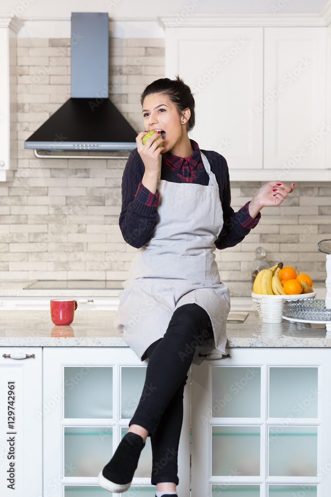 Happy young woman eating apples on kitchen Happy young woman eating apples on kitchen