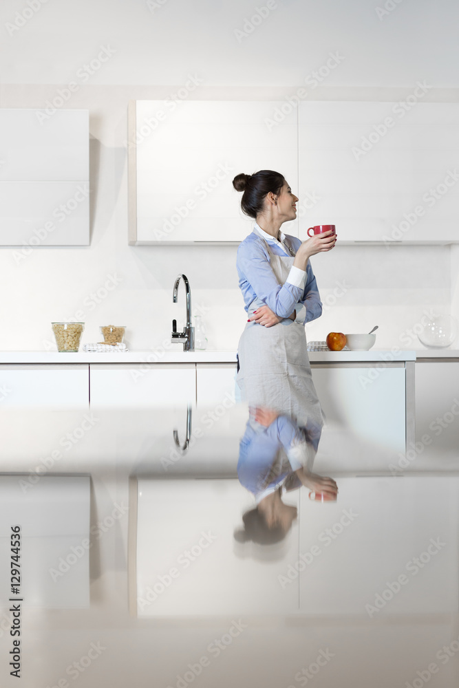 Young woman standing near desk in the kitchen Young woman standing near desk in the kitchen