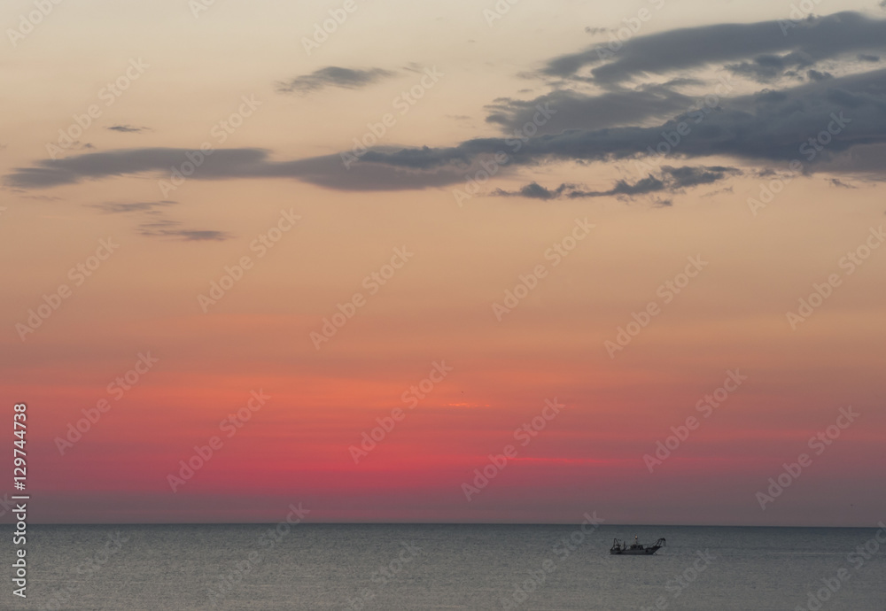 Fototapeta premium Fishing boats pull their nets at the sunrise. Adriatic cost. Emilia Romagna. Italy.