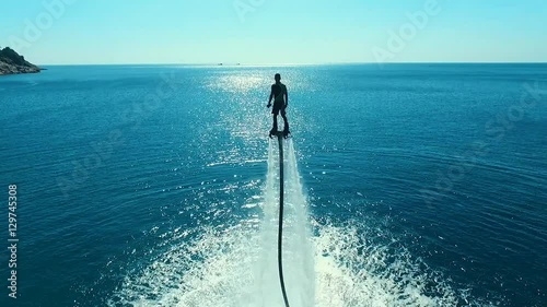 Aerial: Man standing over the water on flyboard.